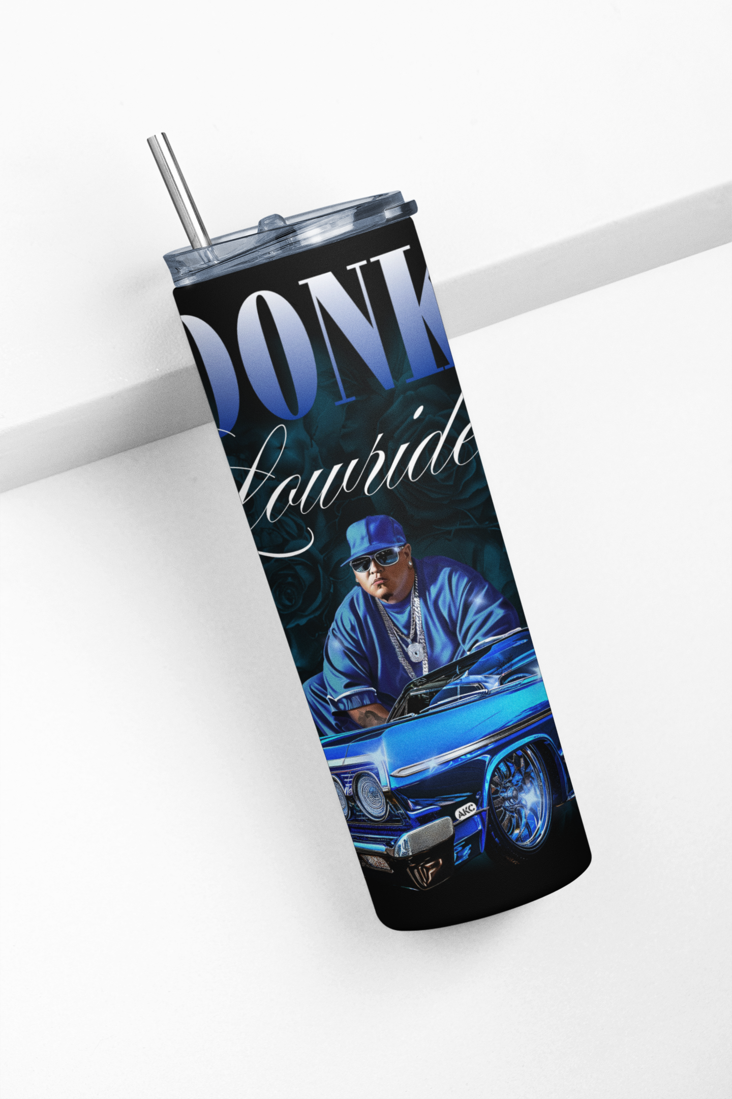 Tumbler with a graphic of a person in a car and text 'Donk Lowrider' on a white surface.