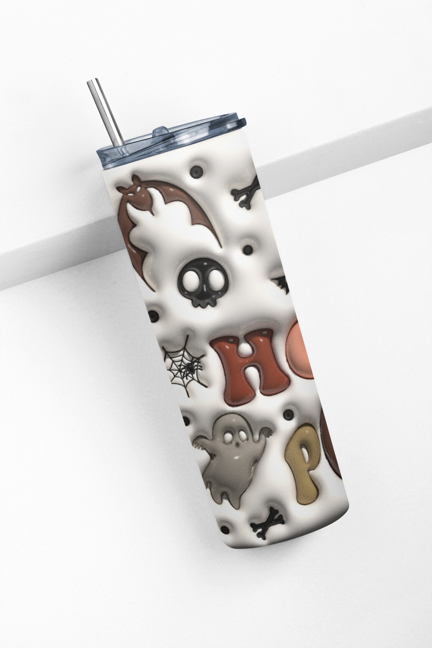 A white insulated tumbler with a Halloween-themed pattern featuring a bat, skull, spiderweb, ghost, and the word 'Halloween' in brown and gray, shown with a clear lid and metal straw on a white background.