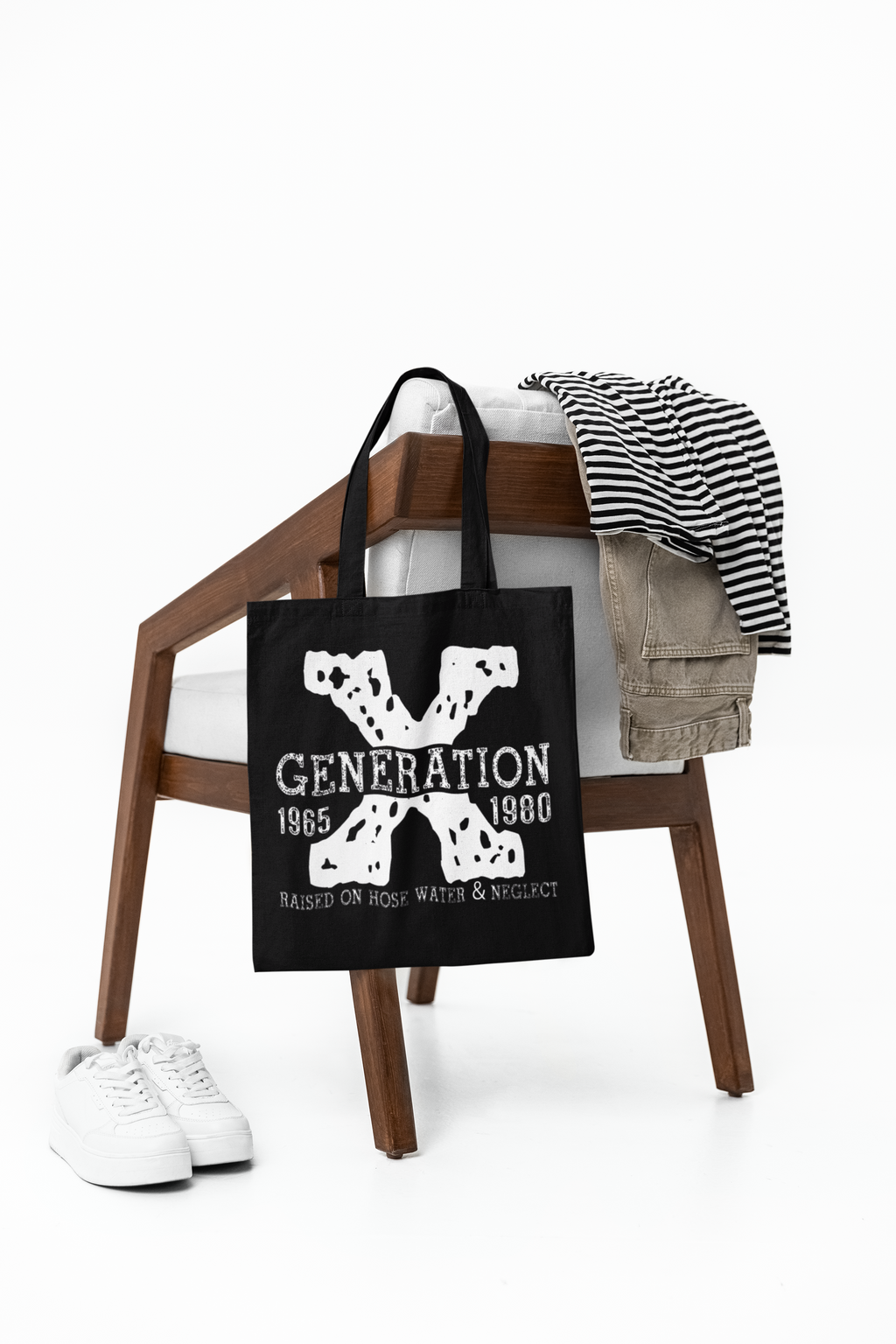 Black tote bag with 'Generation X' design on a wooden stool with clothes and shoes.