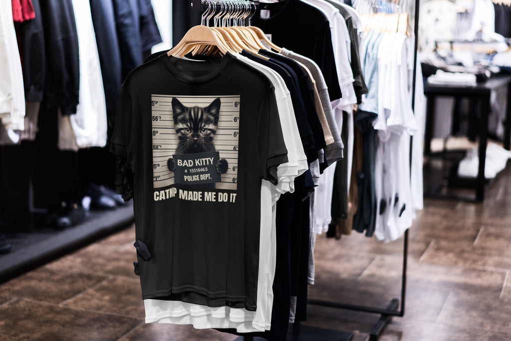 Black t-shirt with a graphic design of a cat and text on a rack in a store.