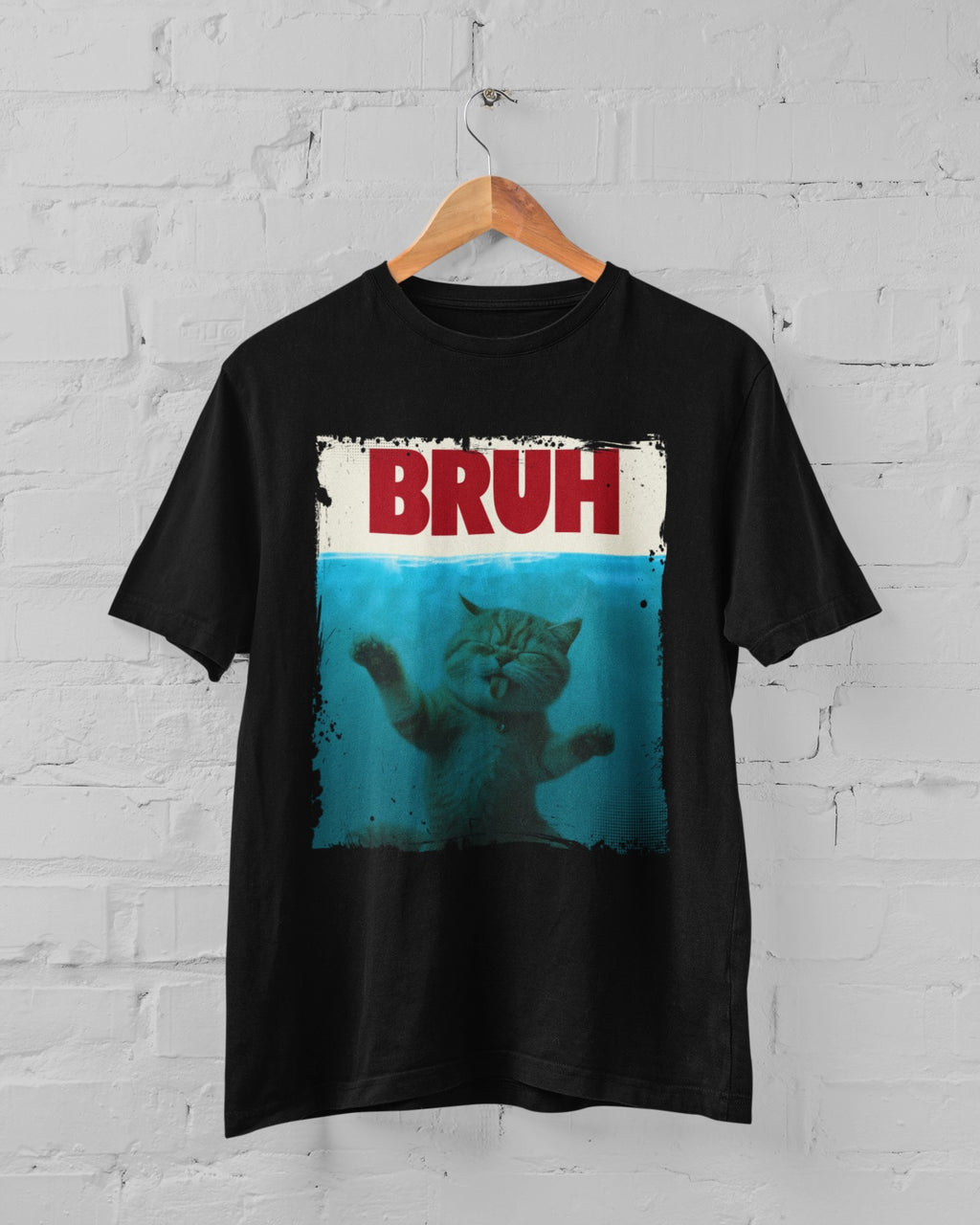 Black t-shirt with a graphic of a cat and 'BRUH' text on a hanger against a white brick wall.