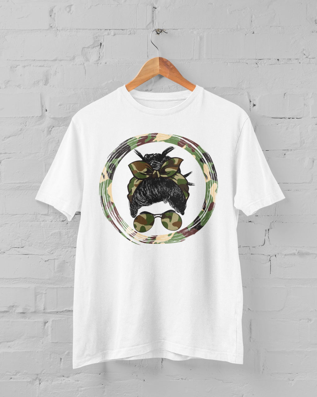 White t-shirt with a graphic design of a dog wearing sunglasses and a camouflage circle on a gray brick wall background.