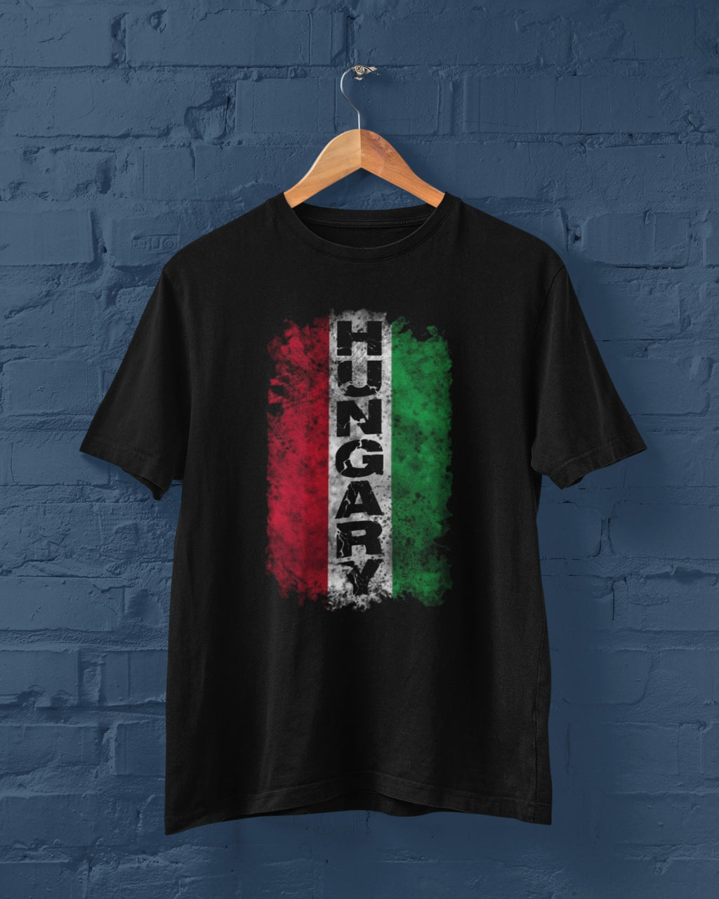 Black t-shirt with Hungarian flag design on a wooden hanger against a blue brick wall.