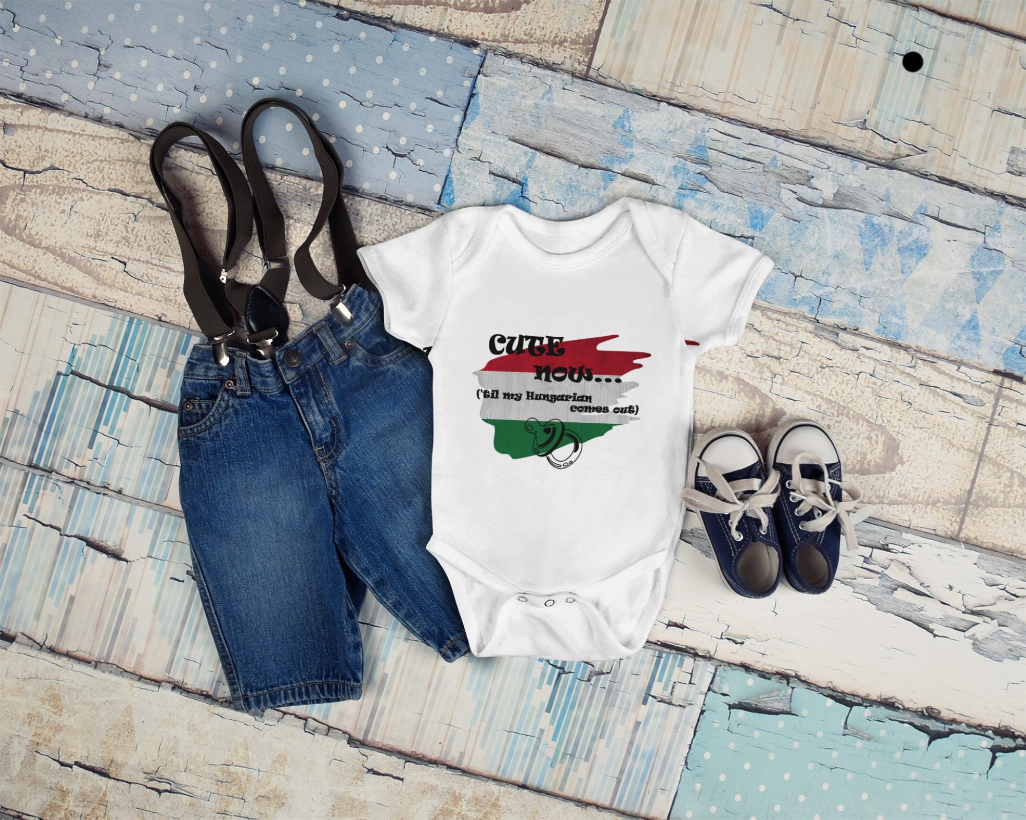 Baby outfit with onesie, jeans, suspenders, and shoes on a wooden surface