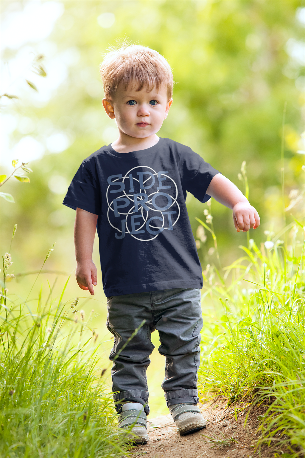 Child walking on a path in a natural setting wearing a dark blue t-shirt with a graphic design.