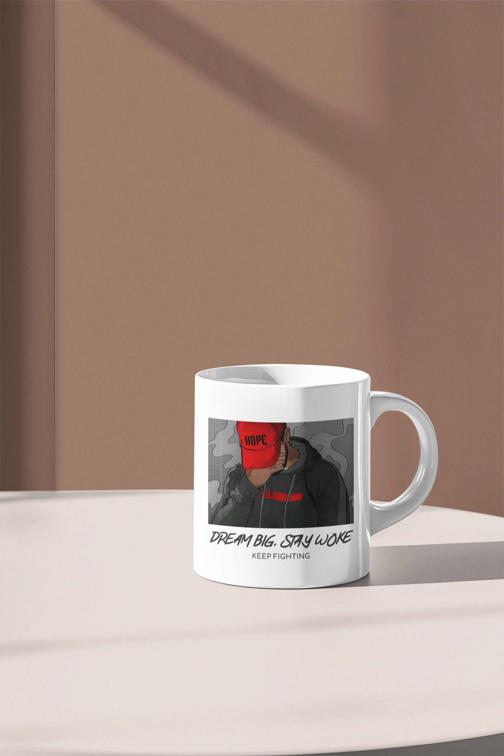 A white ceramic mug with a printed graphic of a person in a black hoodie and red cap, featuring the text 'DREAM BIG. STAY WONE' and 'KEEP FIGHTING'.