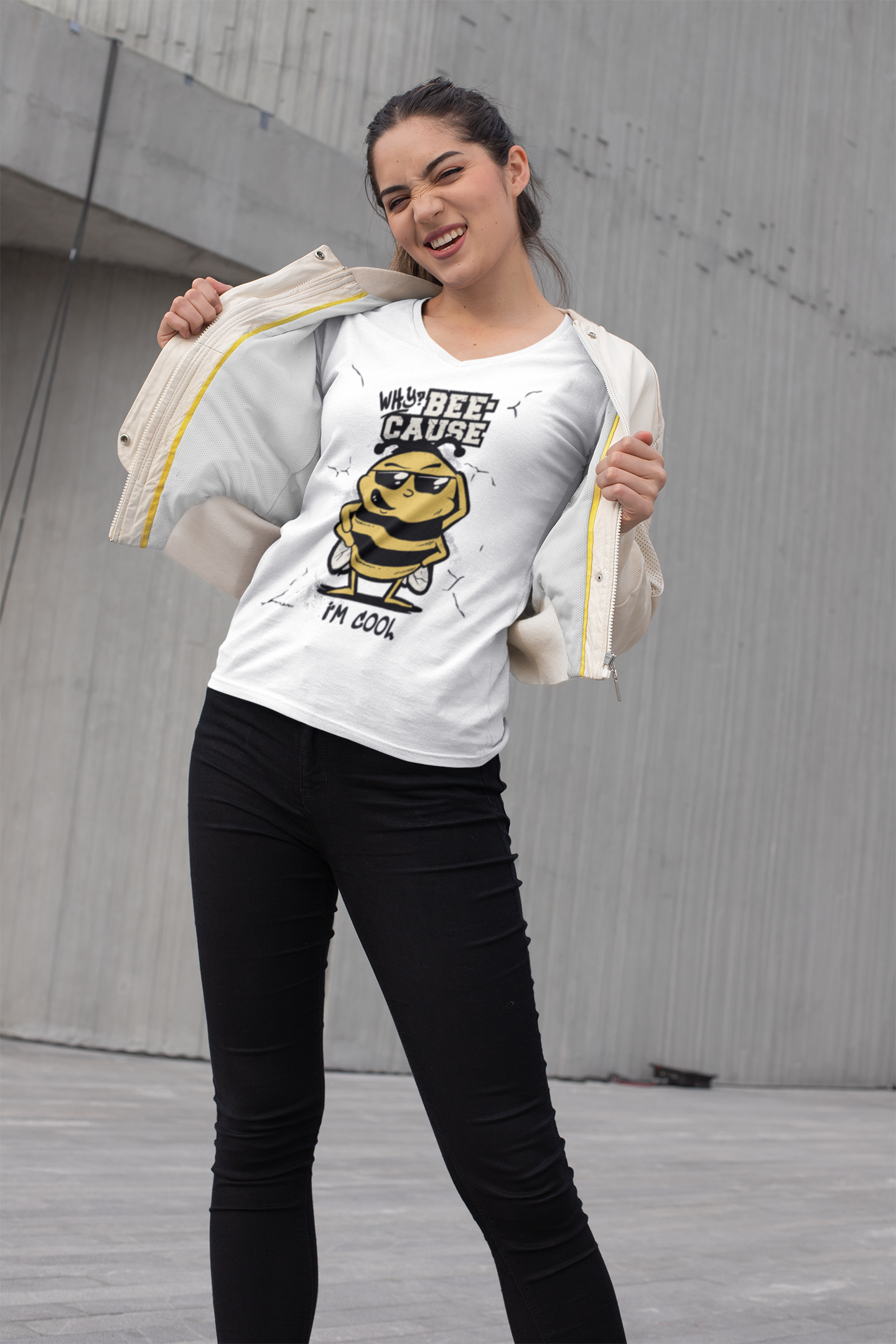 Woman wearing a white t-shirt with a graphic design and text, standing against a concrete wall.