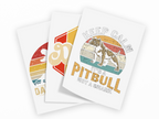 Three overlapping white art prints with distressed retro graphics and text, including a pitbull illustration and the phrase 'KEEP CAZE IT'S A PITBULL NOT A SHARK'.