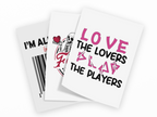 Three white greeting cards with humorous quotes and graphics, fanned out on a plain white background. The front card reads 'LOVE THE LOVERS BLAD THE PLAYERS' in pink and black text.