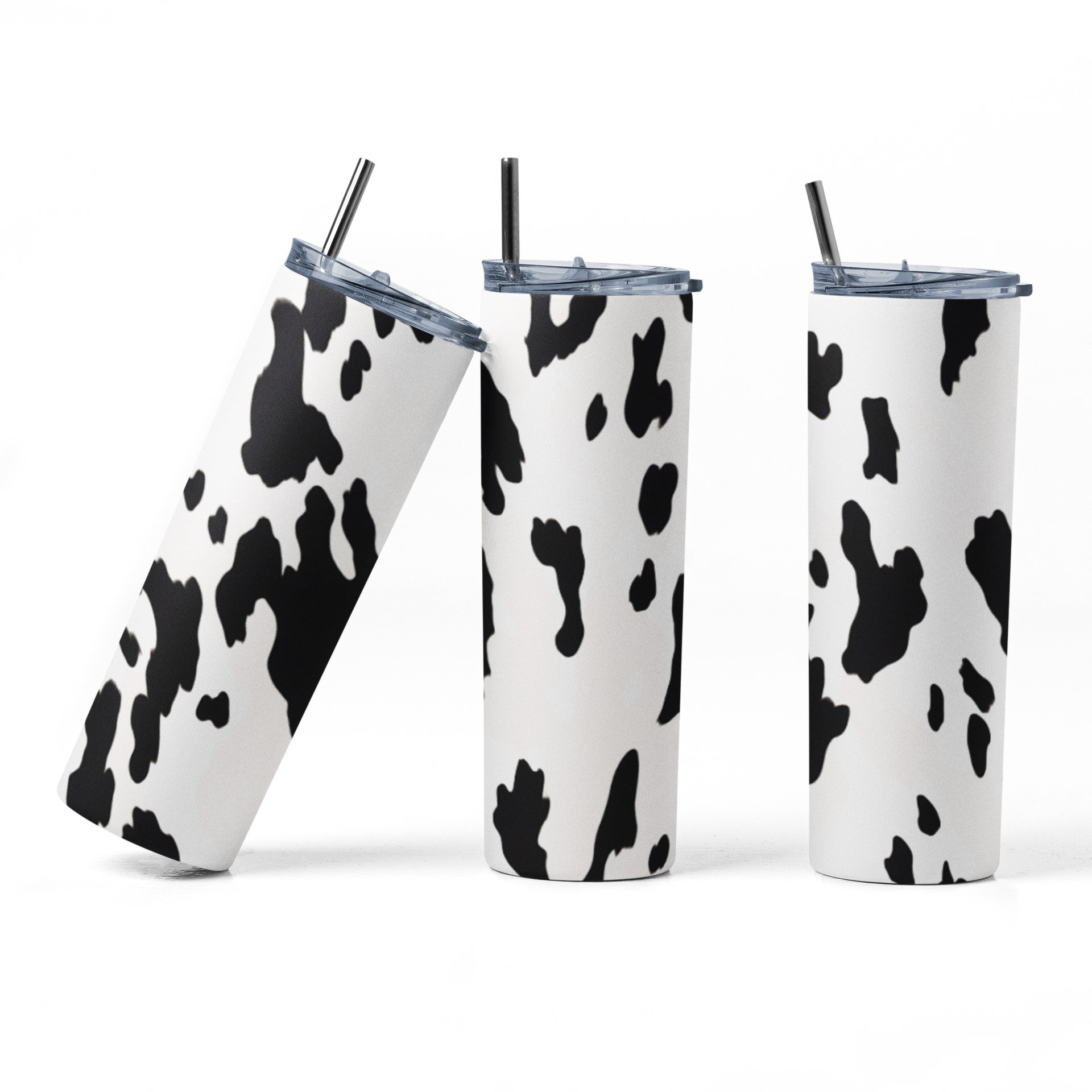Three cow print tumblers with straws on a white background