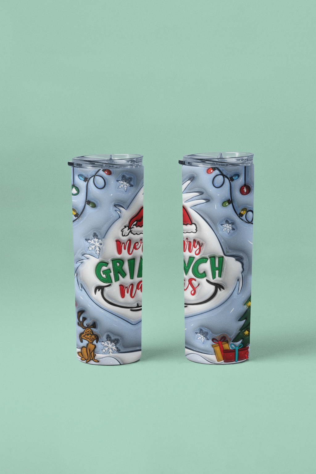 Two slim travel tumbler cups with clear lids, featuring a festive Christmas Grinch design in white, gray, red, and green, set against a solid mint green background.