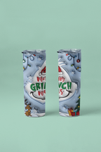 Two slim travel tumbler cups with clear lids, featuring a festive Christmas Grinch design in white, gray, red, and green, set against a solid mint green background.
