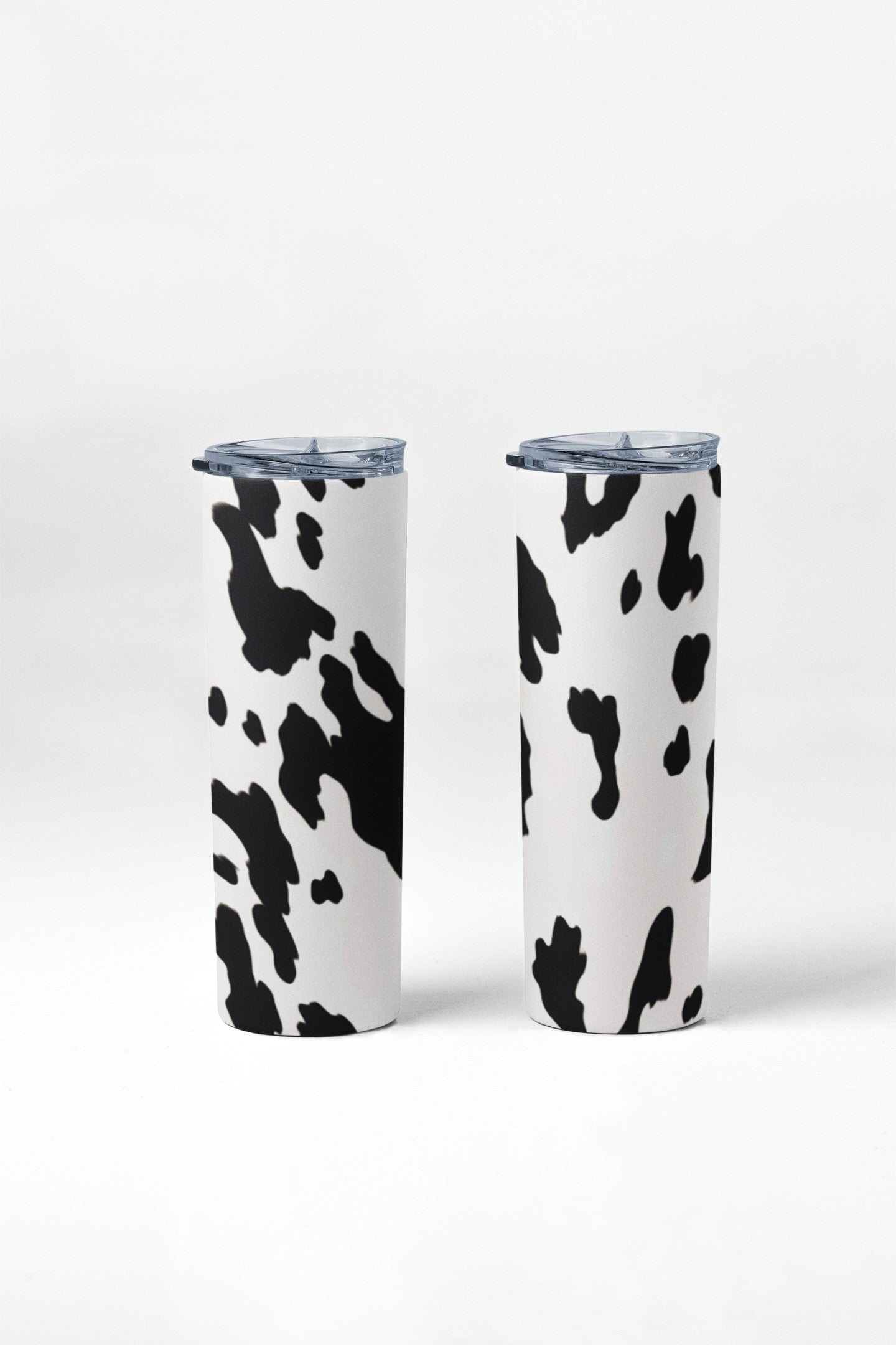 Two tumblers with cow print design on a white background