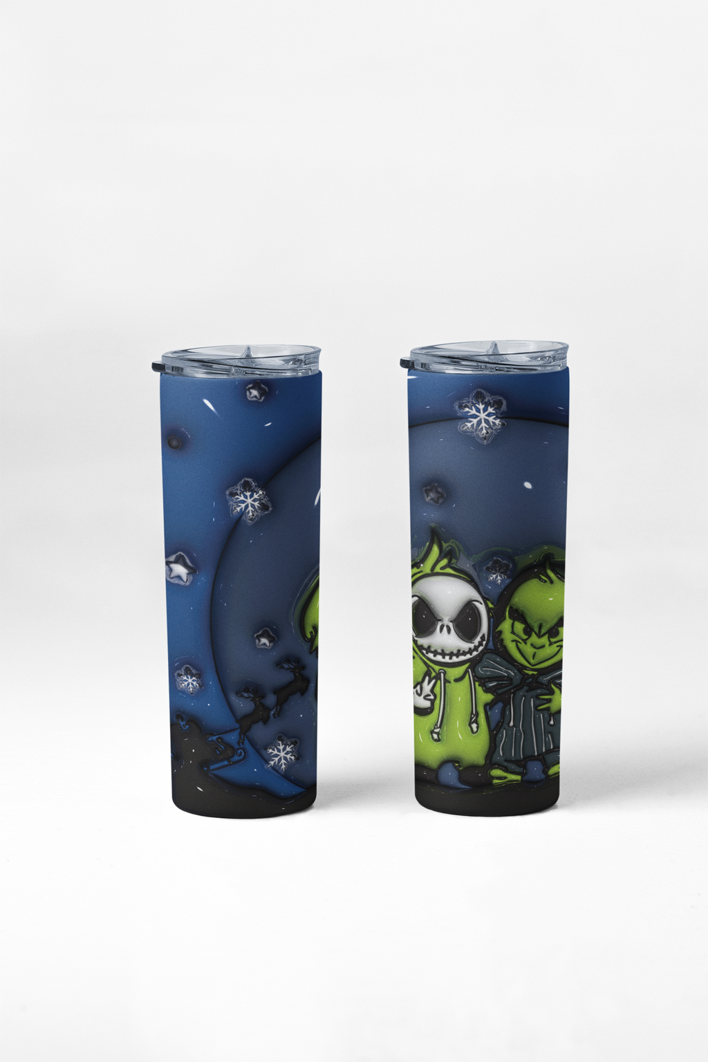Two slim travel tumbler cups with clear lids, featuring a dark blue winter-themed graphic print with snowflakes, a crescent moon, and a green cartoon character on a light gray background.
