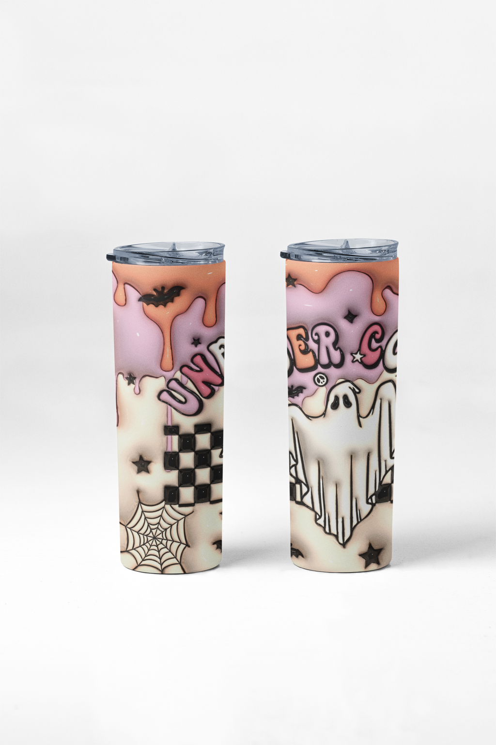 Two slim insulated tumblers with clear lids, printed with a Halloween-themed design featuring pink frosting, orange dripping sauce, ghosts, spiders, stars, and a black-and-white checkerboard pattern on a light gray studio background.