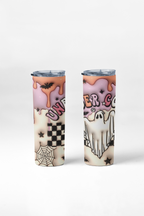 Two slim insulated tumblers with clear lids, printed with a Halloween-themed design featuring pink frosting, orange dripping sauce, ghosts, spiders, stars, and a black-and-white checkerboard pattern on a light gray studio background.