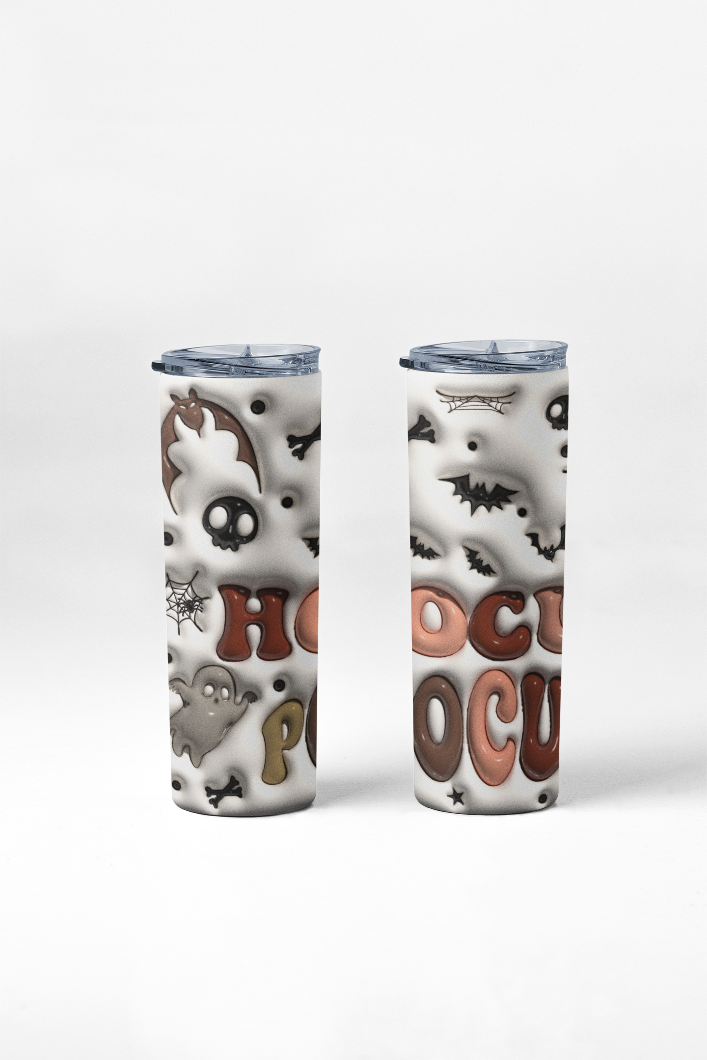 Two slim travel tumbler cups with clear lids, decorated with a white background and a spooky Halloween pattern including bats, skulls, ghosts, and the words 'HOCU POCA' in brown and pink letters.