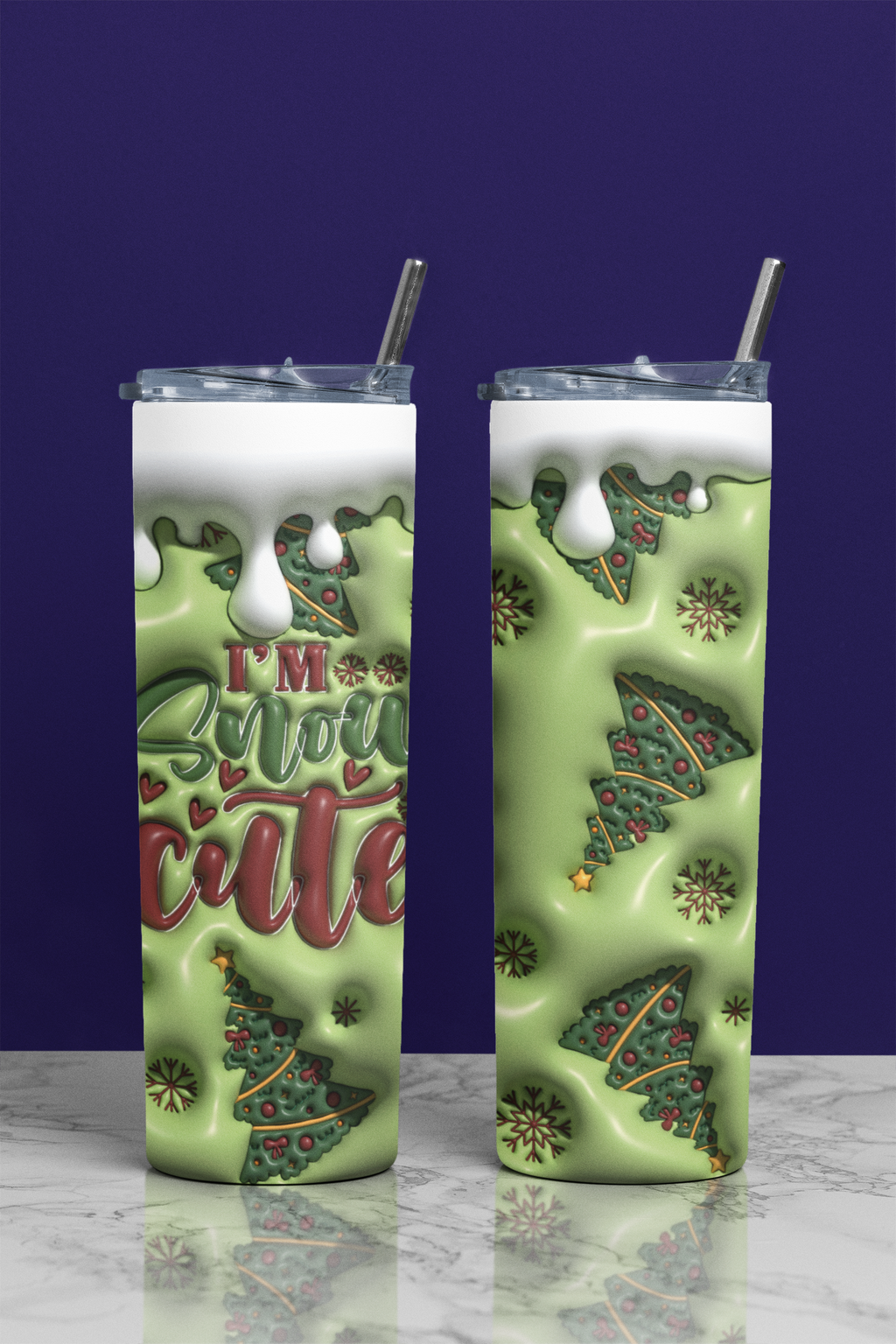 Two tall skinny tumblers with clear lids and metal straws, shown on a marble surface against a dark purple background. The tumblers have a light green holiday design with Christmas trees, snow, and the text 'I'm So Snow Cute' in red and green.