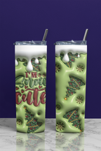 Two tall skinny tumblers with clear lids and metal straws, shown on a marble surface against a dark purple background. The tumblers have a light green holiday design with Christmas trees, snow, and the text 'I'm So Snow Cute' in red and green.