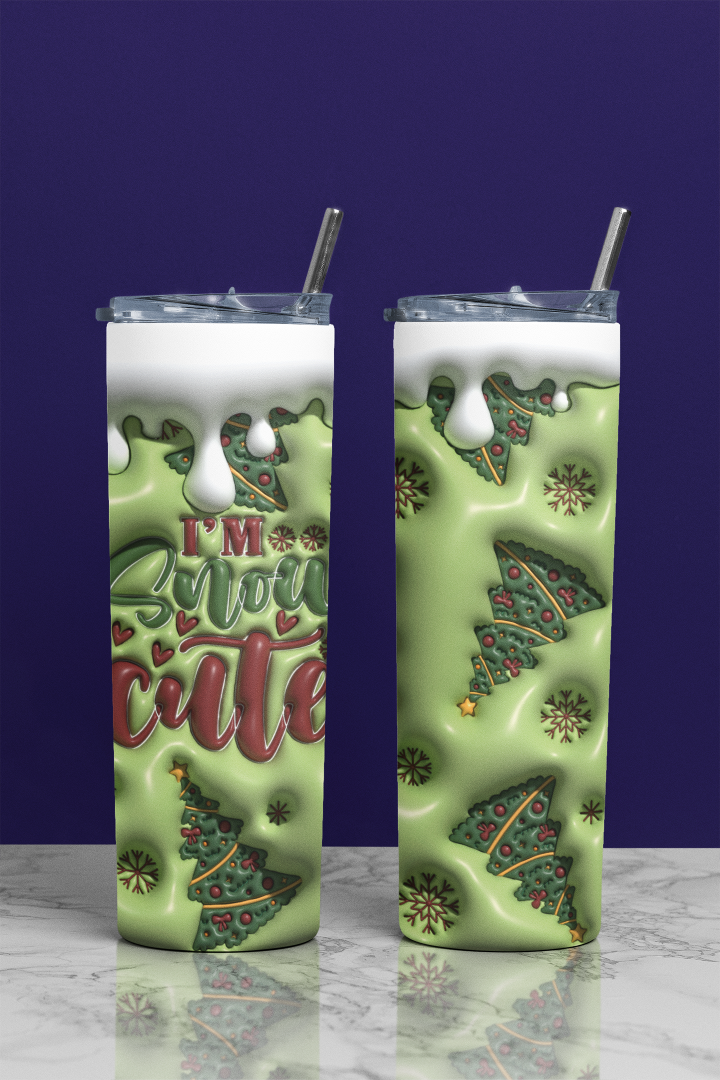 Two tall skinny tumblers with clear lids and metal straws, shown on a marble surface against a dark purple background. The tumblers have a light green holiday design with Christmas trees, snow, and the text 'I'm So Snow Cute' in red and green.