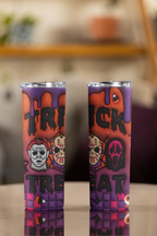 Two purple and orange Halloween-themed insulated tumblers with a 'TRICK or TREAT' design, displayed on a reflective table surface with a blurred indoor background.