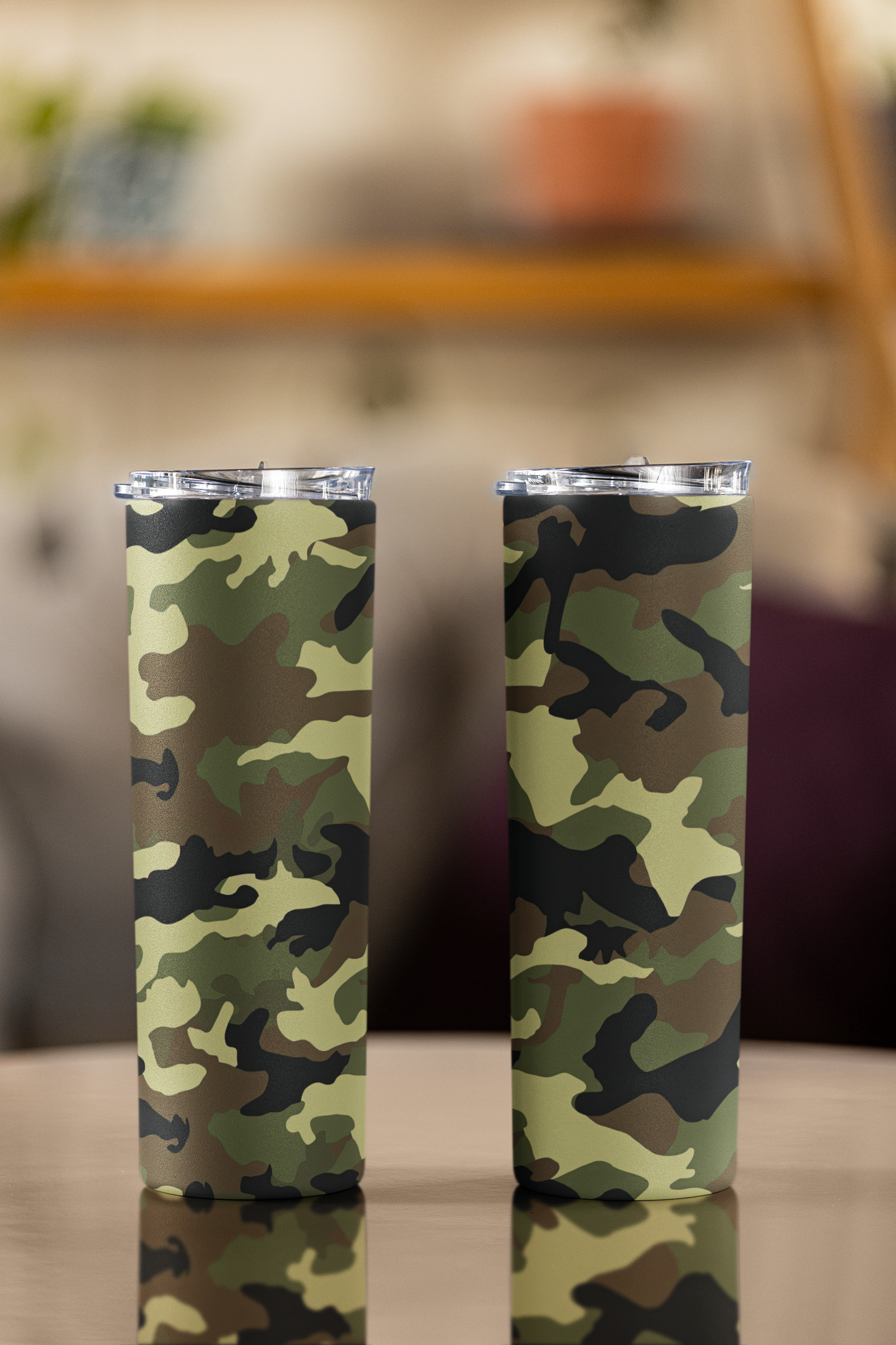 Two camouflage-patterned tumblers on a blurred background