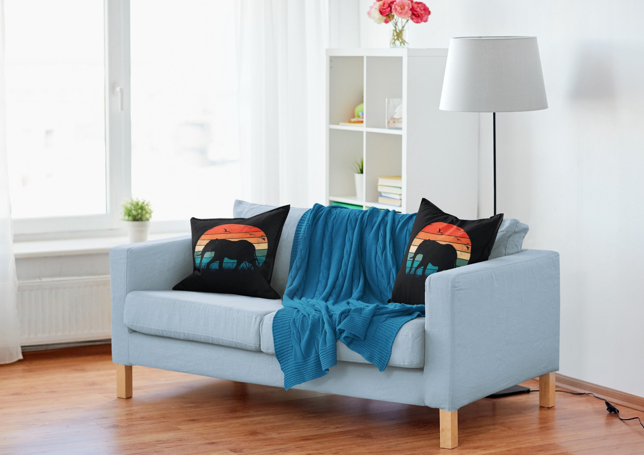 Light blue sofa with black pillows featuring colorful designs in a living room setting.