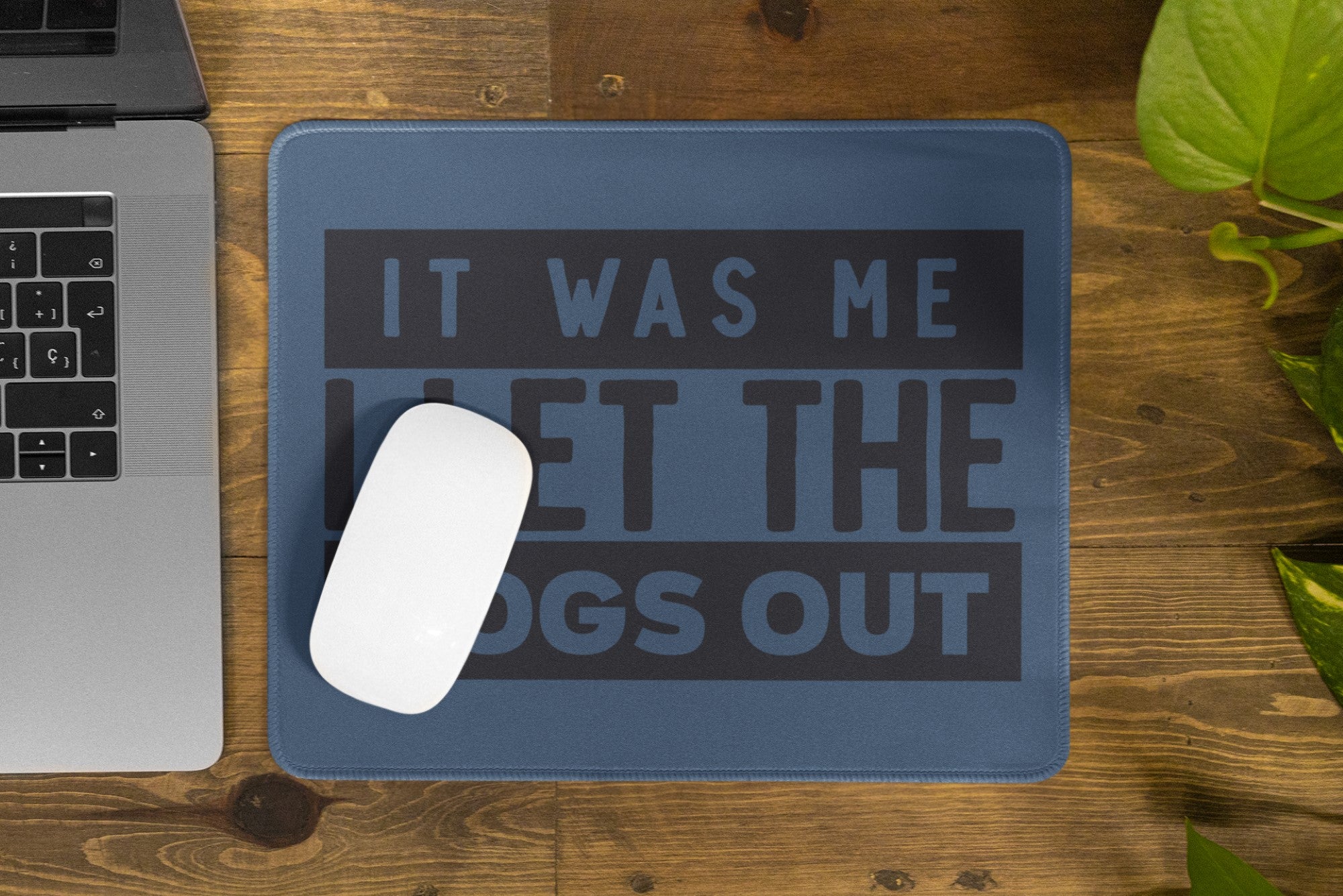 Mouse pad with humorous text on a wooden desk next to a laptop