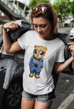 Woman wearing a white t-shirt with a bear graphic in sunglasses and a blue outfit, standing outdoors.