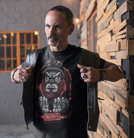 Man wearing a black t-shirt with a graphic design, standing against a wooden wall.
