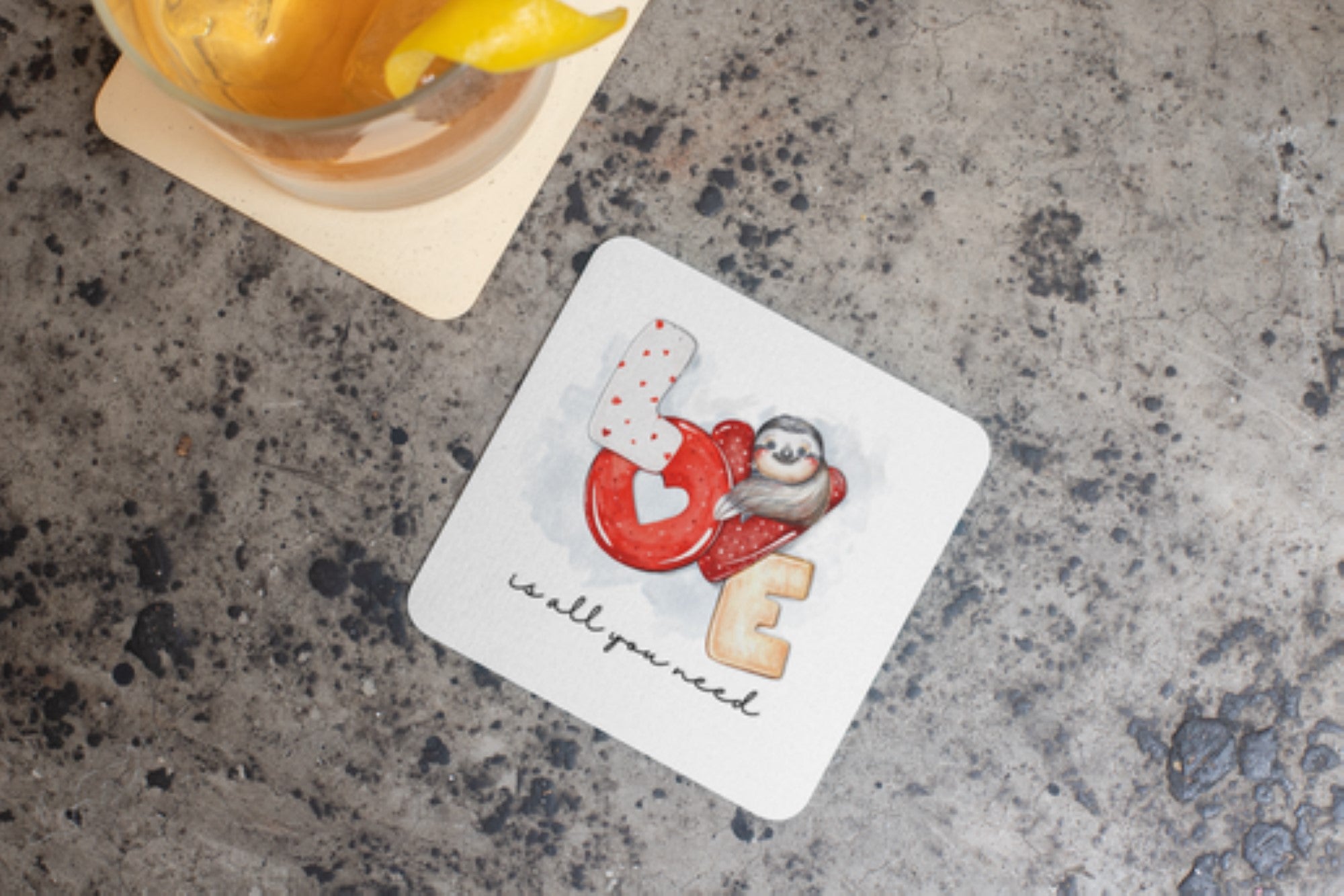 White mug with a design of a sloth, heart, and cookie on a marble surface.