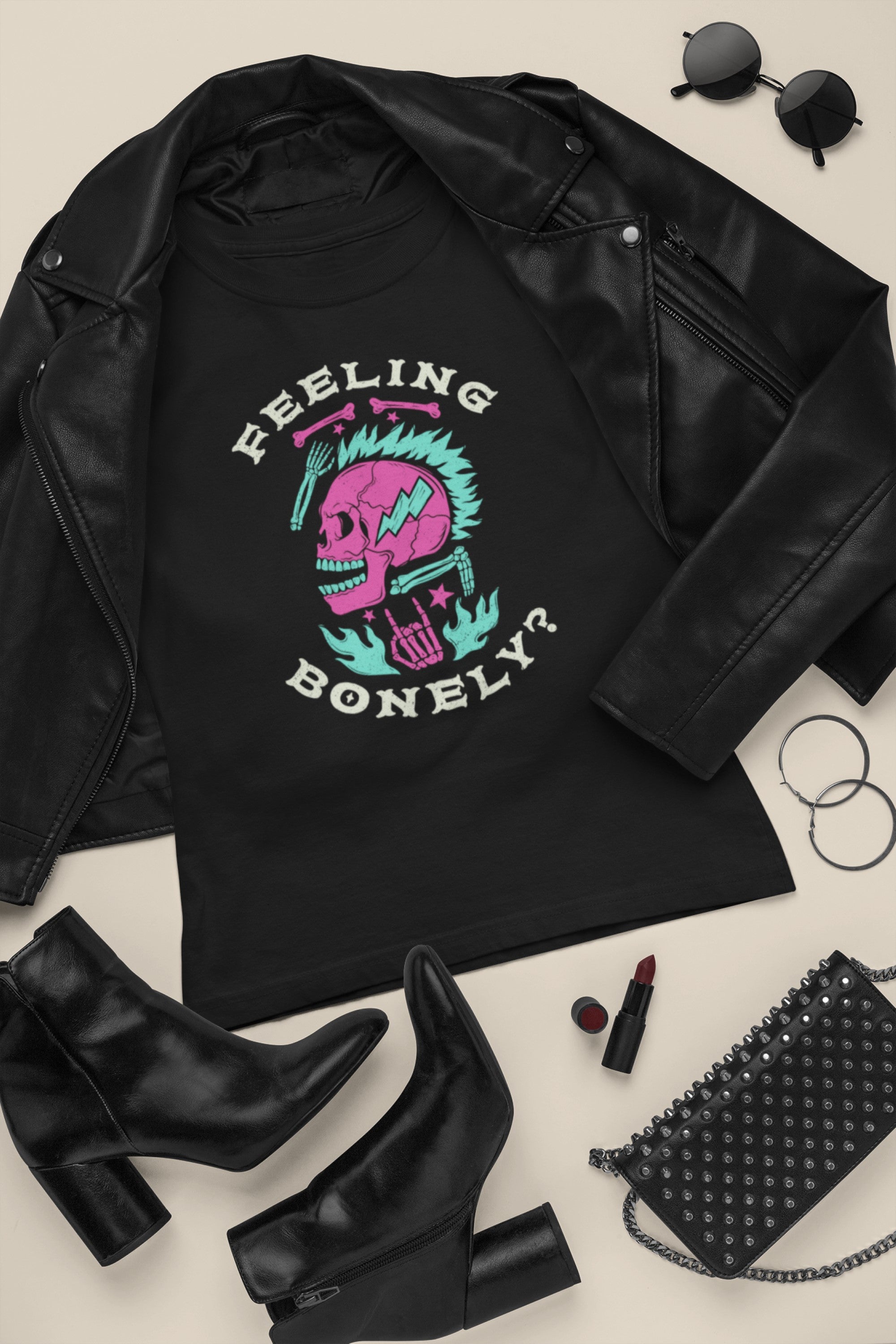 Black t-shirt with skull design and text 'Feeling Bonely?' on a black leather jacket with accessories.