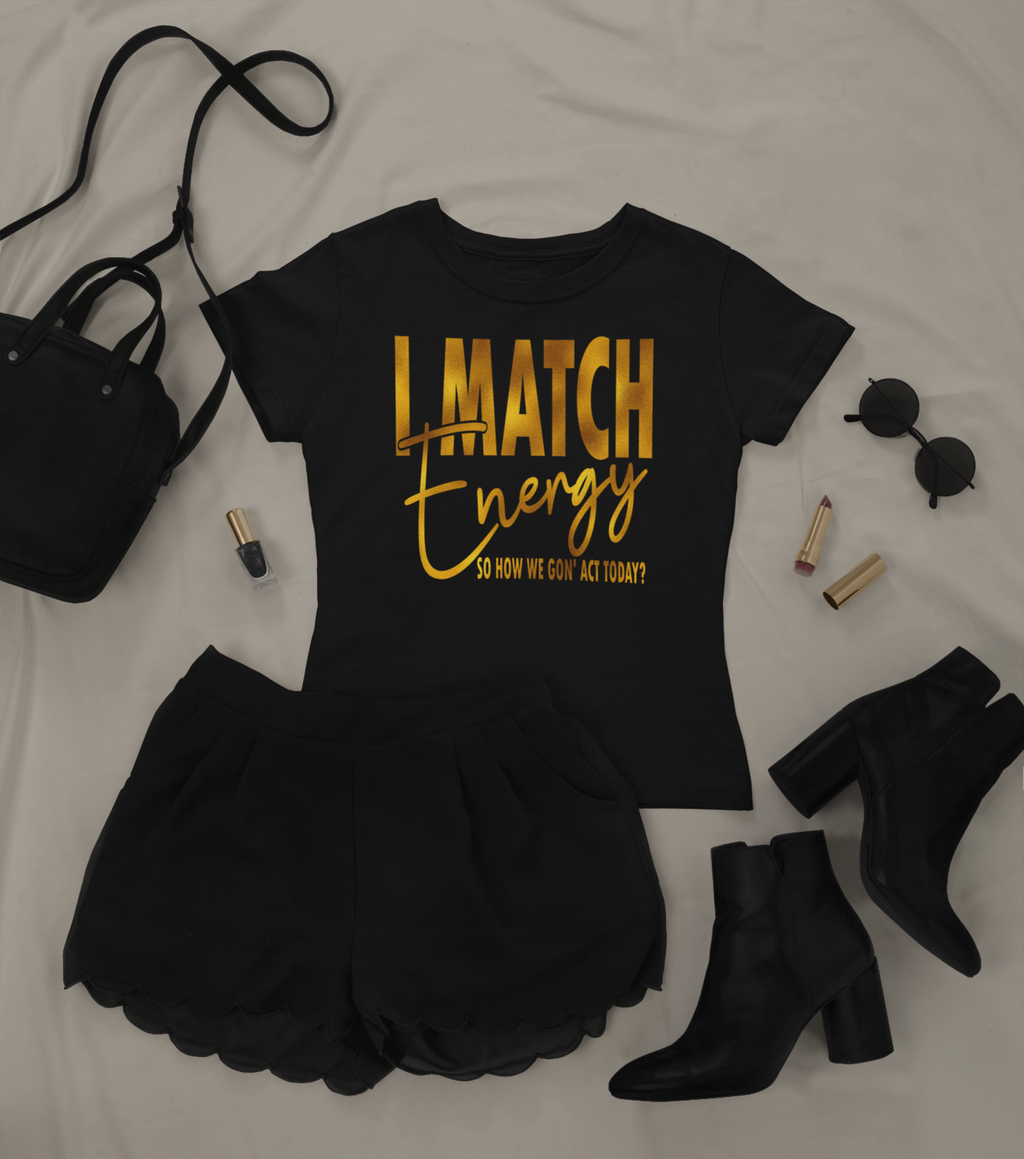 Black t-shirt with 'I Match Energy' text, black skirt, black boots, and accessories on a light gray background