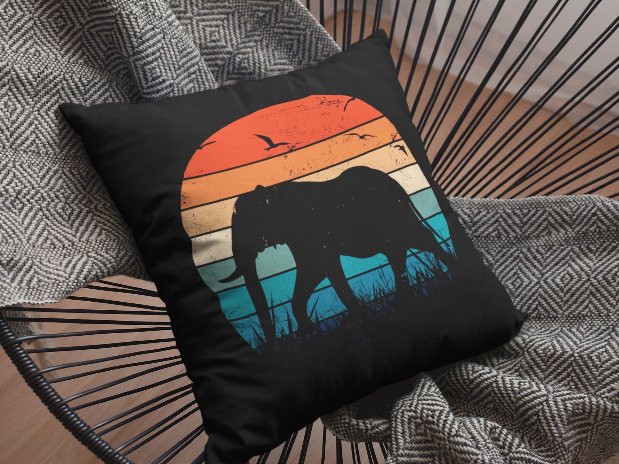 Decorative pillow with elephant and sunset design on a chair