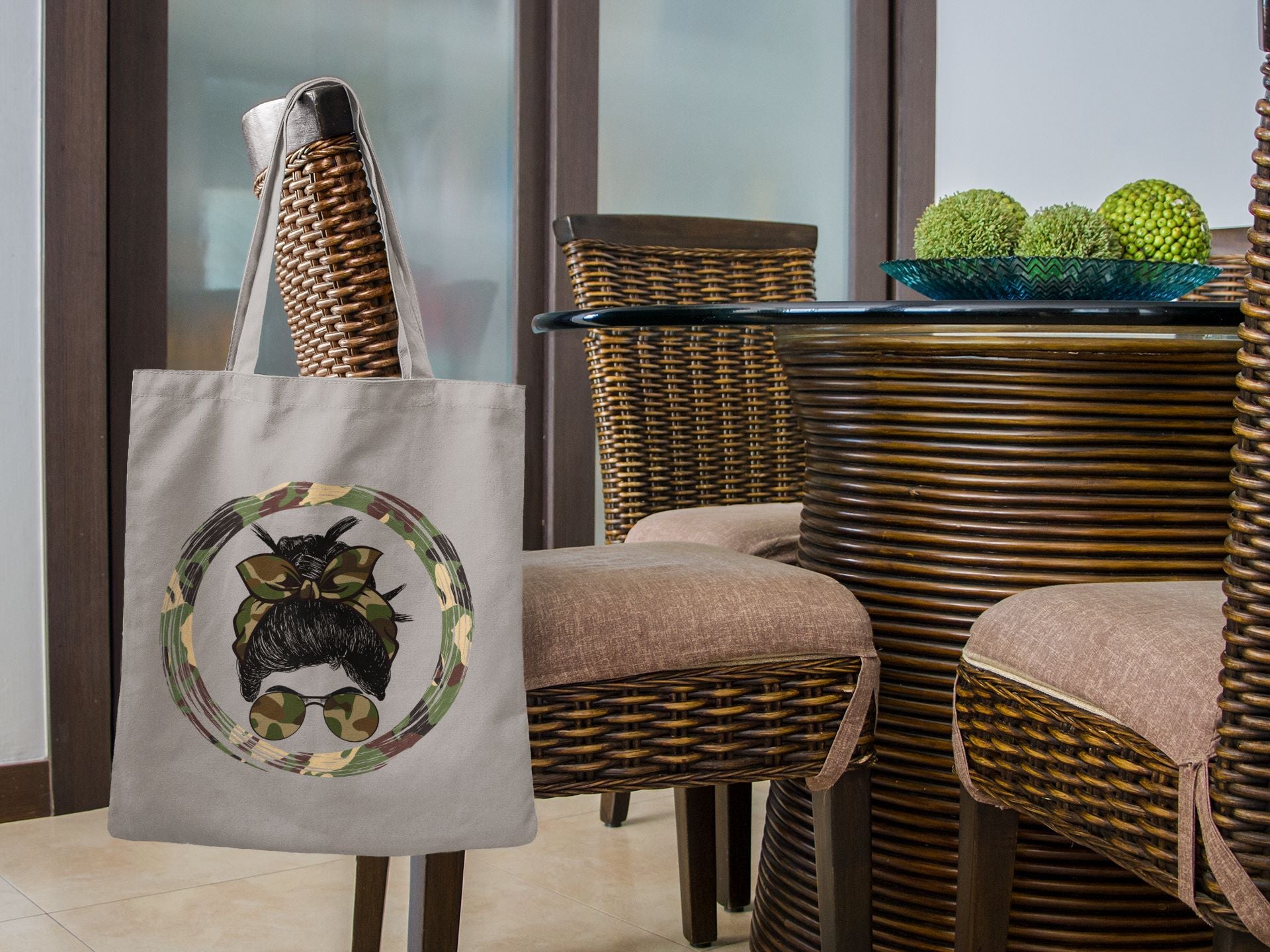 Tote bag with a cat design in front of a wicker chair and table set.