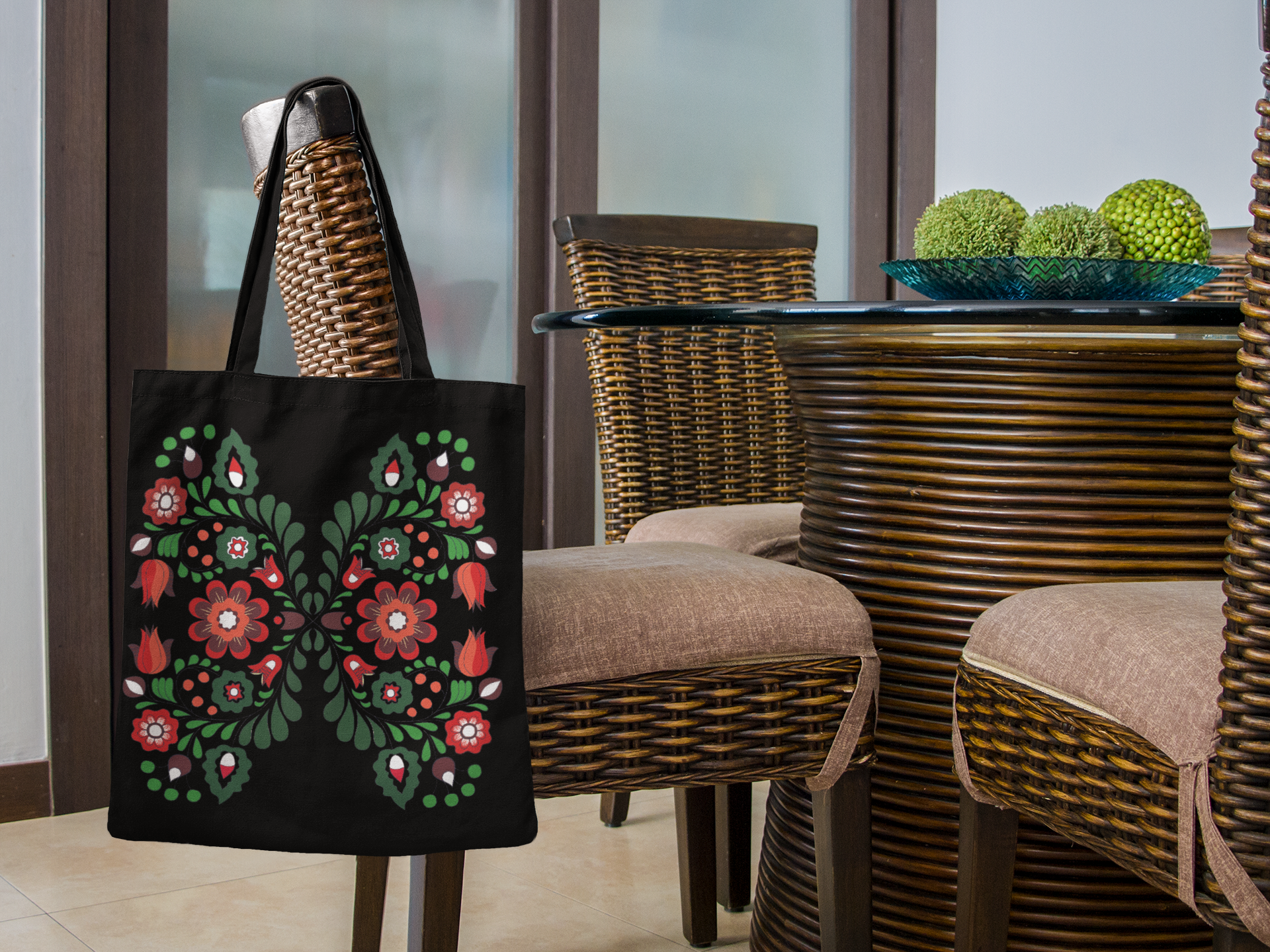 Black tote bag with floral design on a wicker chair in an outdoor setting