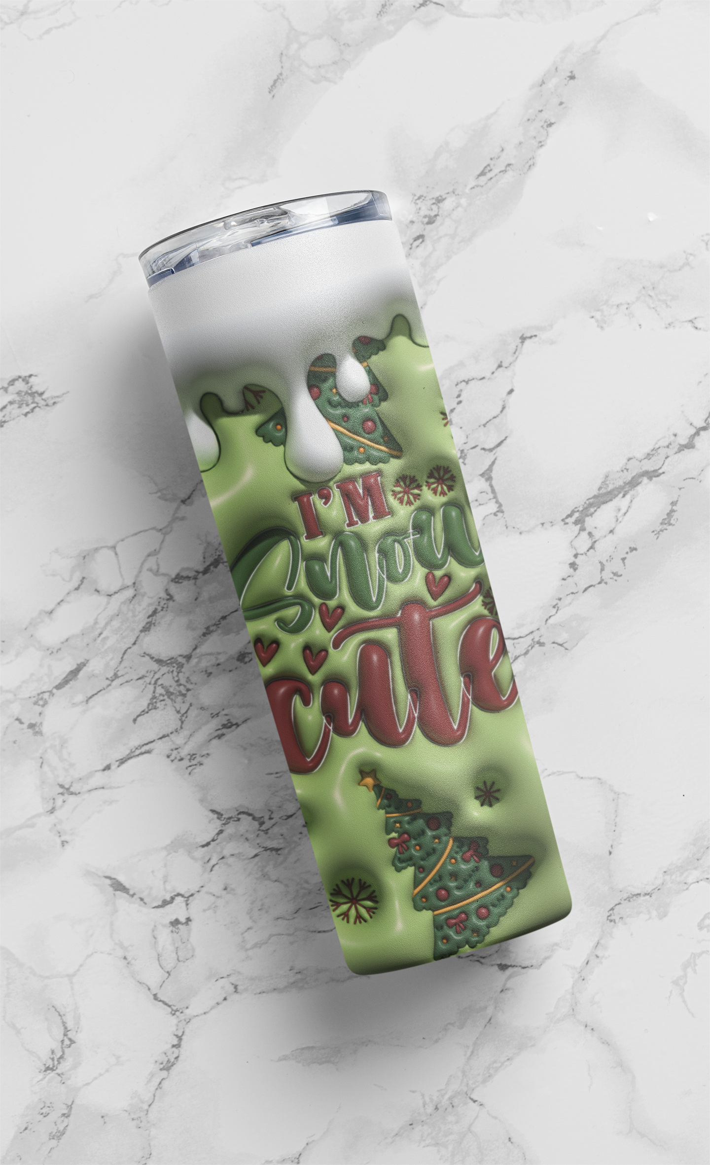 A tall insulated tumbler with a clear lid, featuring a green holiday design with dripping white liquid, red script text reading 'I'M Your cute', and a Christmas tree illustration, shown on a white marble surface.