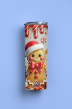 A slim stainless steel tumbler with a clear lid, featuring a festive Christmas gingerbread man print, set against a solid light blue background.