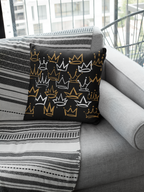 Decorative pillow with crown pattern on a gray sofa with striped blanket