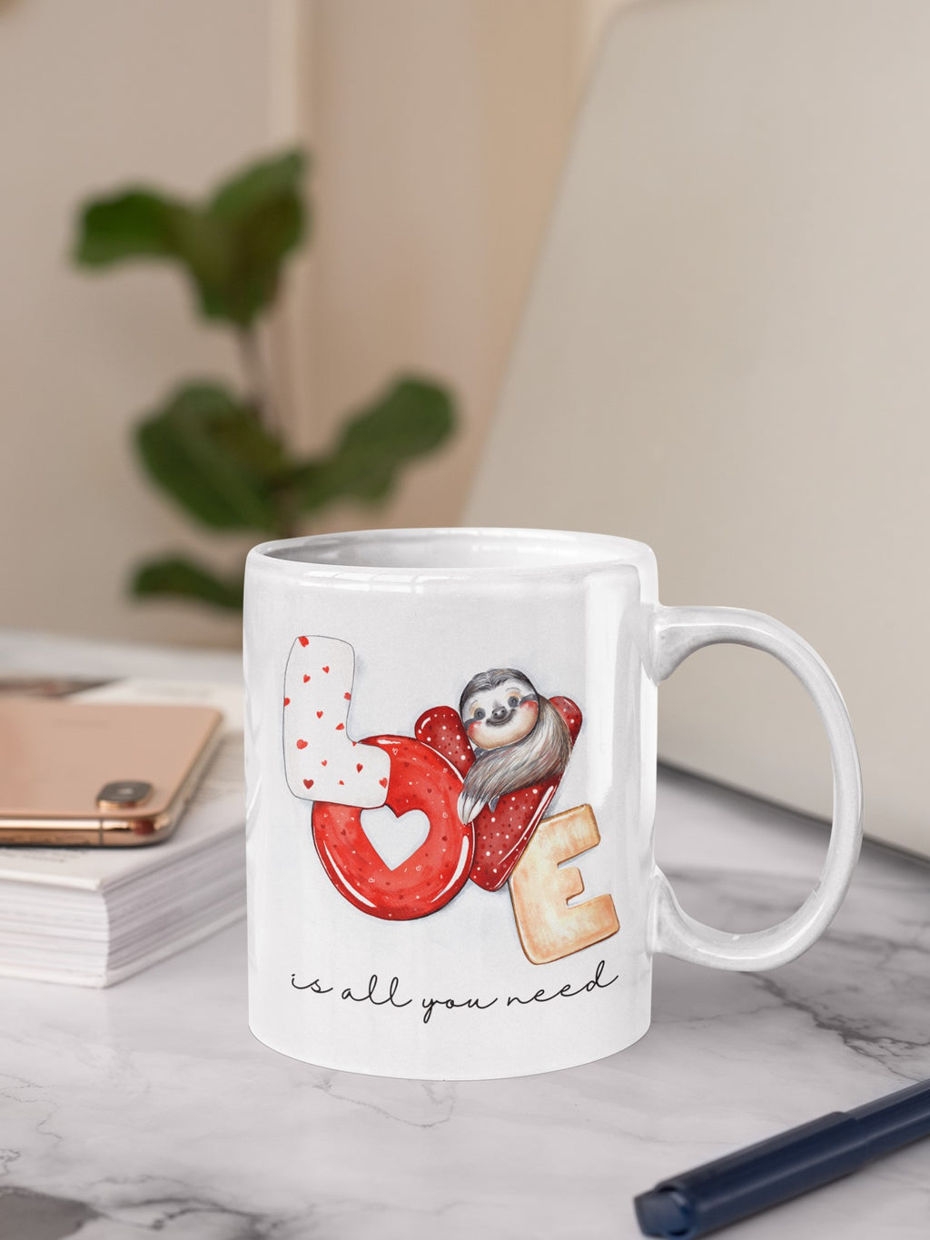 White mug with a design of a sloth, heart, and cookie on a marble surface.