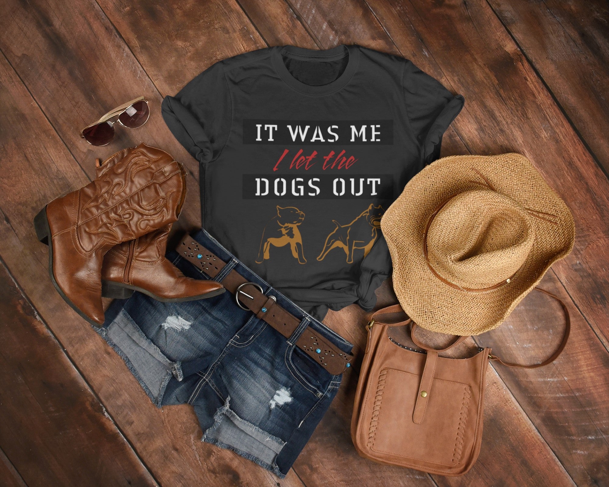 Black t-shirt with humorous text, cowboy boots, hat, and purse on a wooden surface