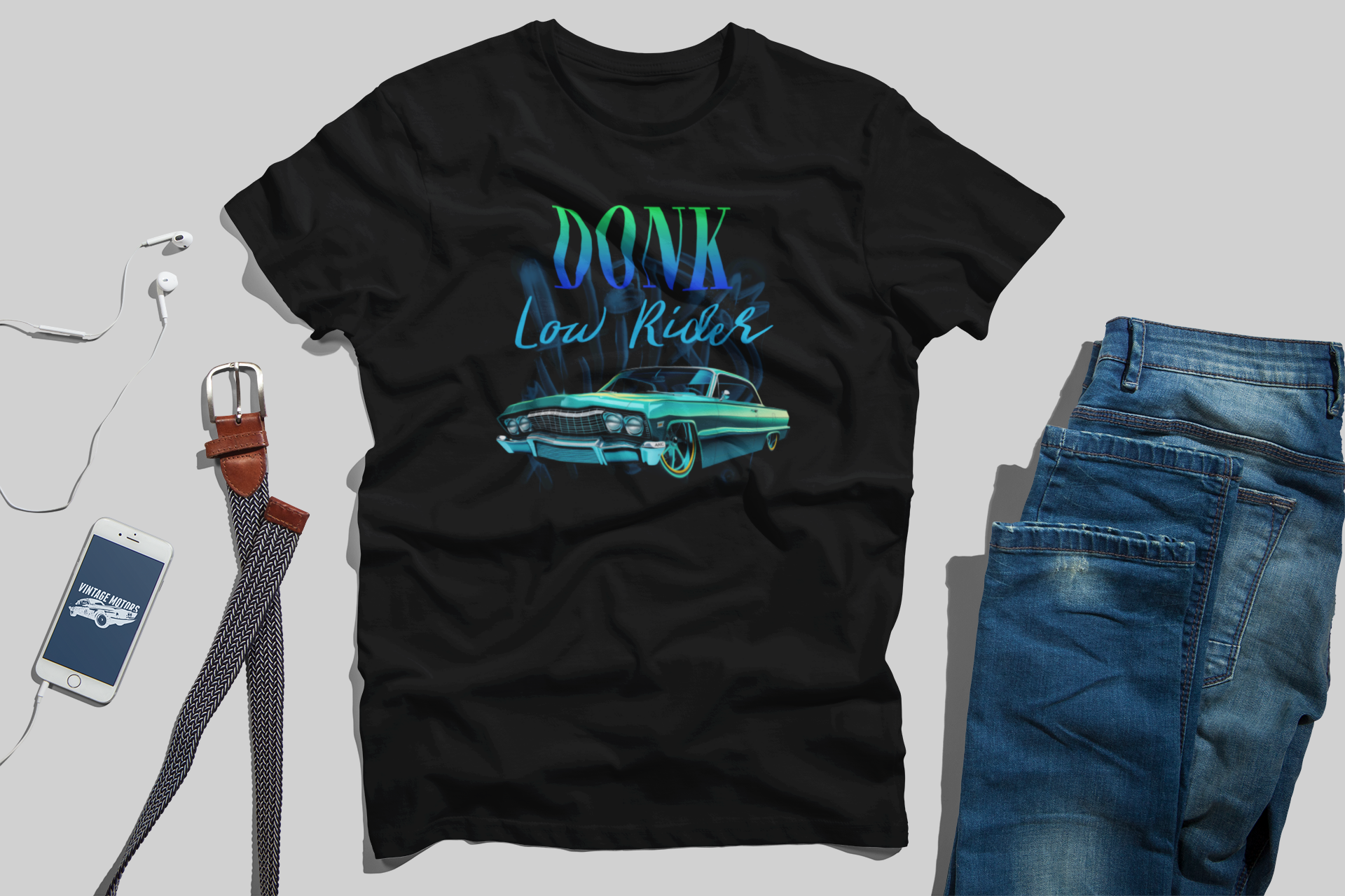 Black t-shirt with 'Donk Low Rider' graphic, blue jeans, smartphone, and belt on a light gray background