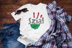 White t-shirt with 'Szia!' design on a wooden surface with jeans and a plaid shirt.