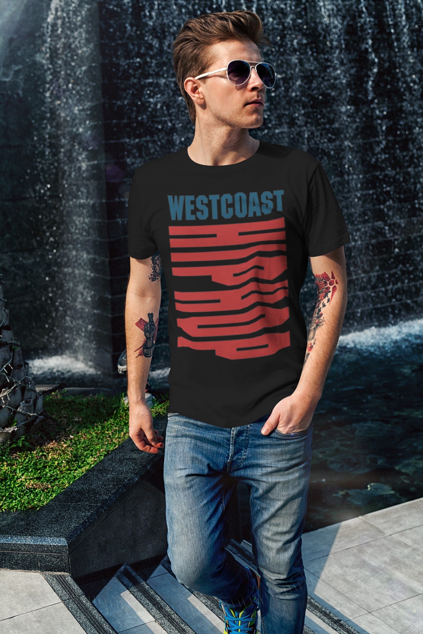 Man wearing a black t-shirt with 'Westcoast' design in front of a water fountain.