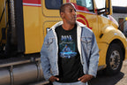 Man wearing a black t-shirt with graphic design and text, standing in front of a yellow truck.