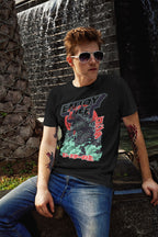 Person wearing a black t-shirt with graphic design and sunglasses, sitting in front of a water fountain.