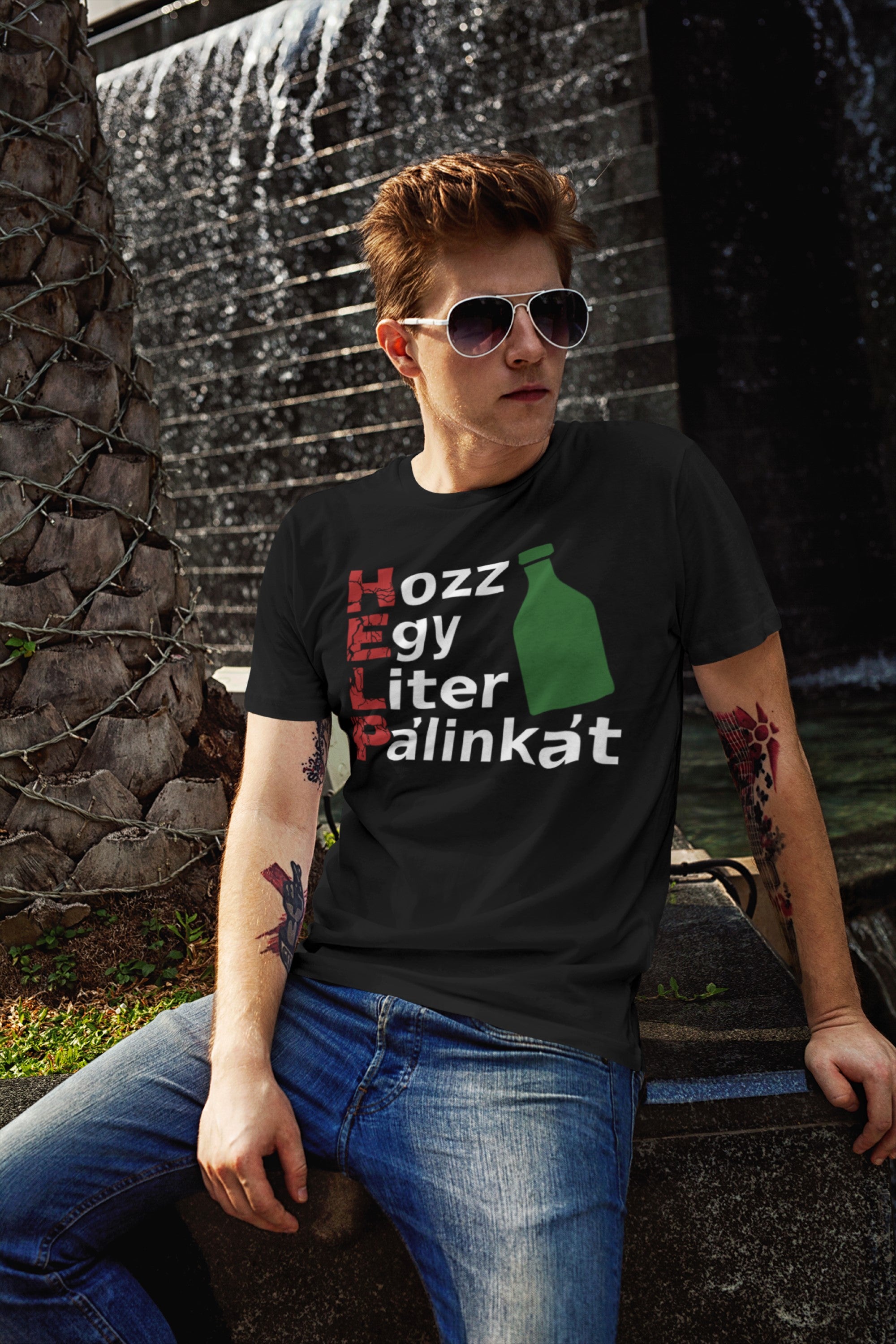 Person wearing a black t-shirt with text and graphics, sitting in front of a water fountain.