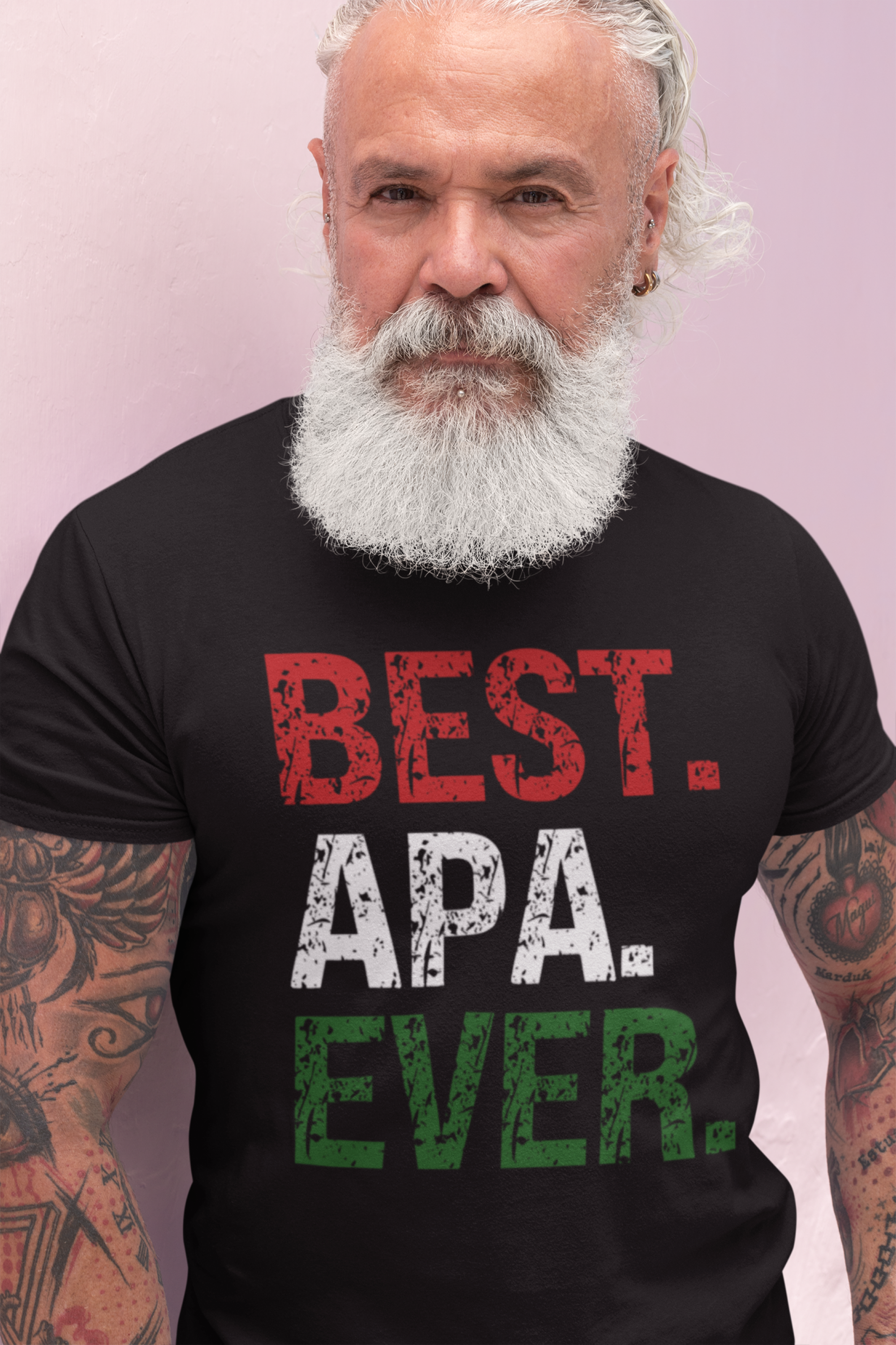 A man with a white beard and tattoos wearing a black t-shirt with the text 'BEST. APA.
