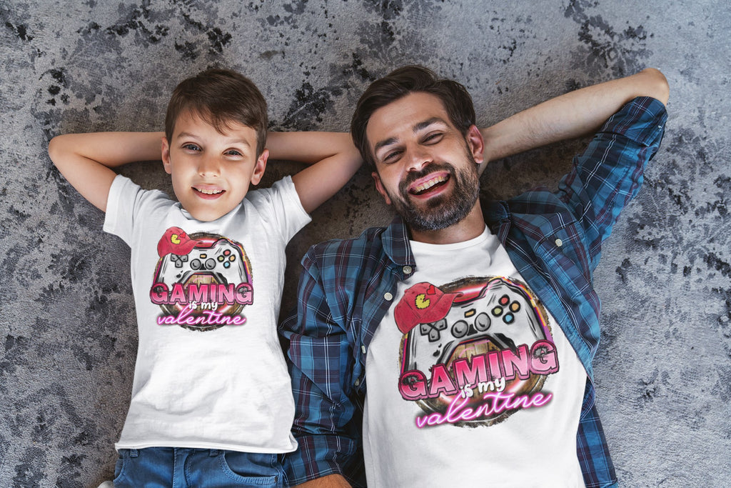 Man and child lying on a textured surface wearing matching 'Gaming my Valentine' shirts.