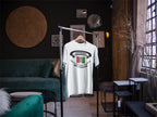 White t-shirt with graphic design on a hanger in a room with furniture and decor.